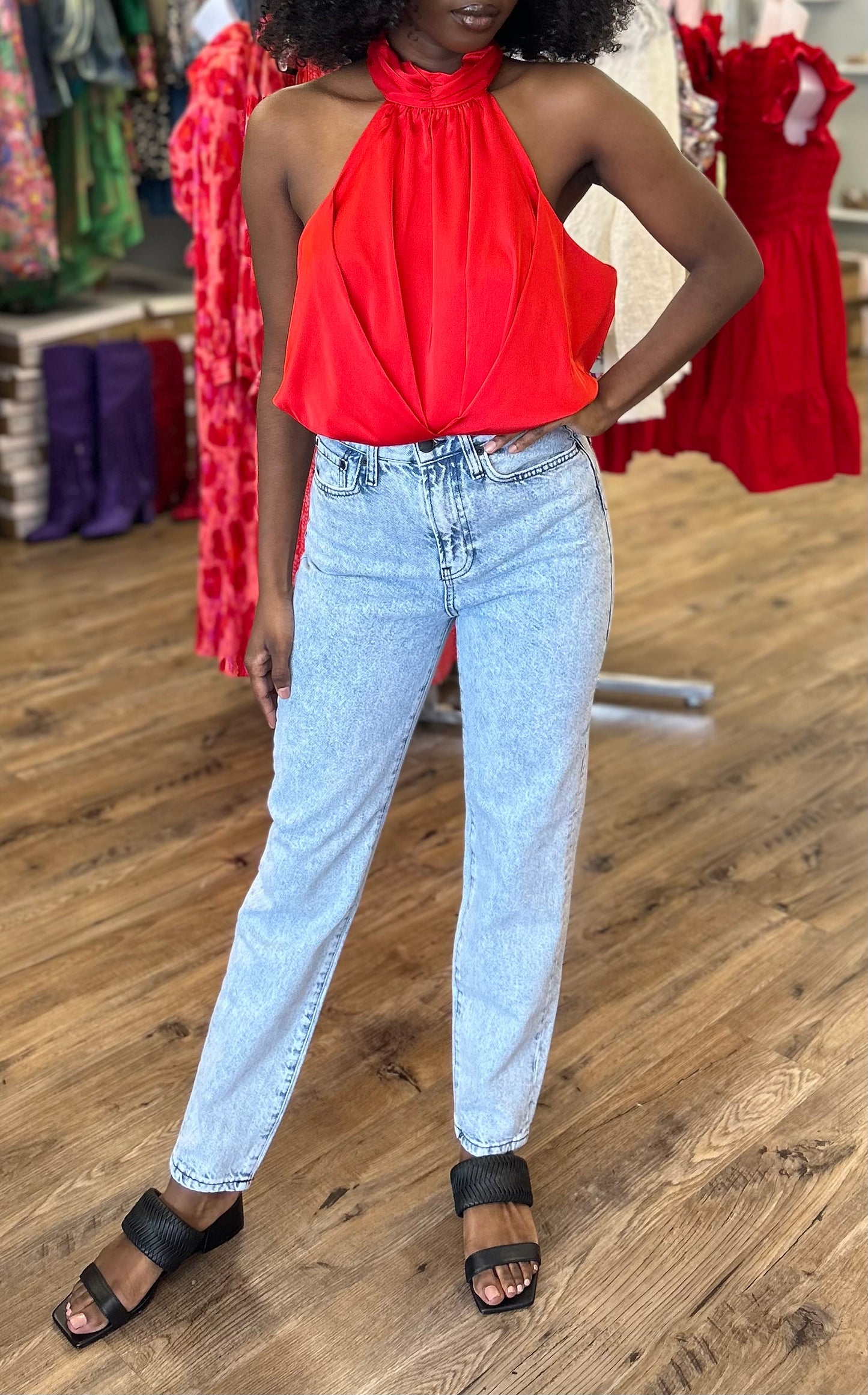 Model wearing Cherry Bomb Jeans in light blue denim with cherry on pocket, featuring a high-rise waist, wide leg fit, and raw hem detailing.