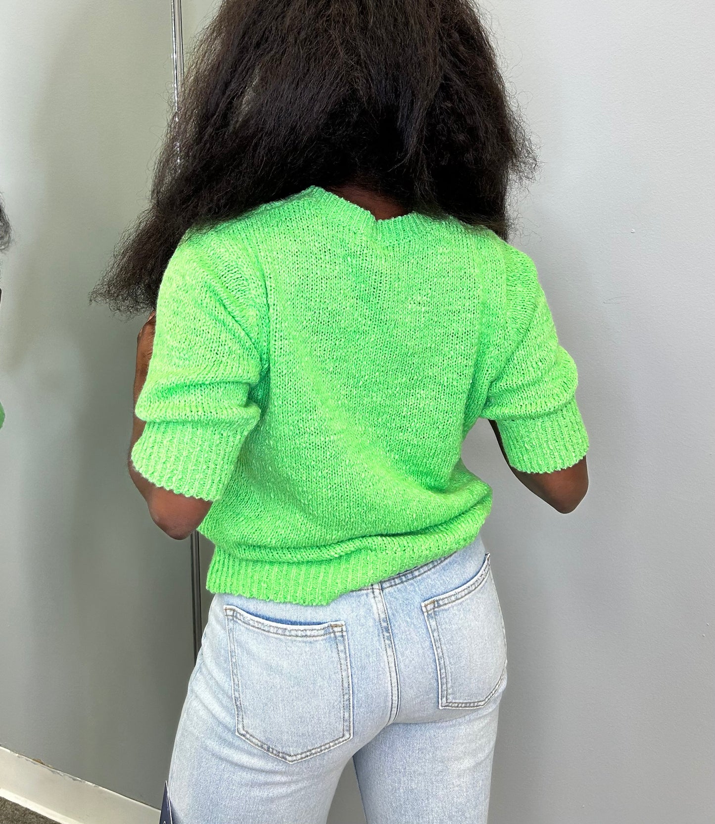 Model wearing the Chloris Top in vibrant green, featuring puff sleeves, ruched bodice, and a square neckline, styled with light denim jeans.