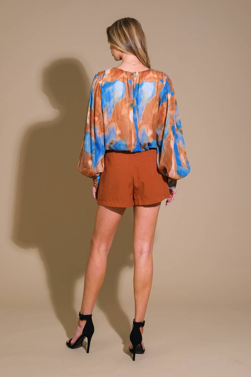 Model wearing the Evermore Woven Top in brown and blue abstract pattern, featuring a relaxed fit and lightweight fabric.