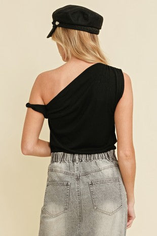 Woman wearing a black one-shoulder top paired with a high-waisted faded gray denim skirt and black newsboy cap – styled look for Sloan's Formal Boutique.