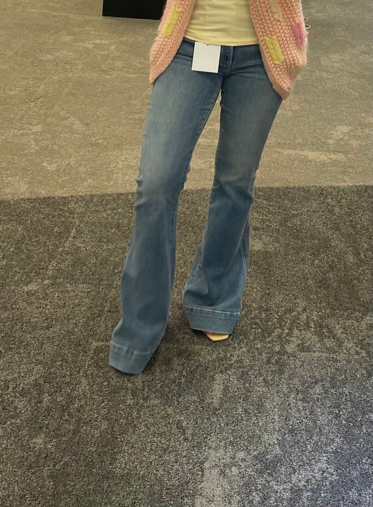 Model wearing Kinsley Flare Jeans in light wash denim, featuring a high-rise fit, flared leg, and vintage-inspired fading