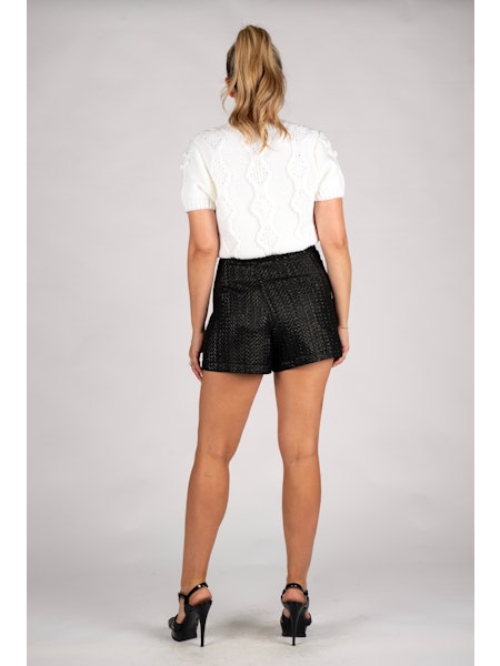 Woman wearing a white top and black shorts on a gray background