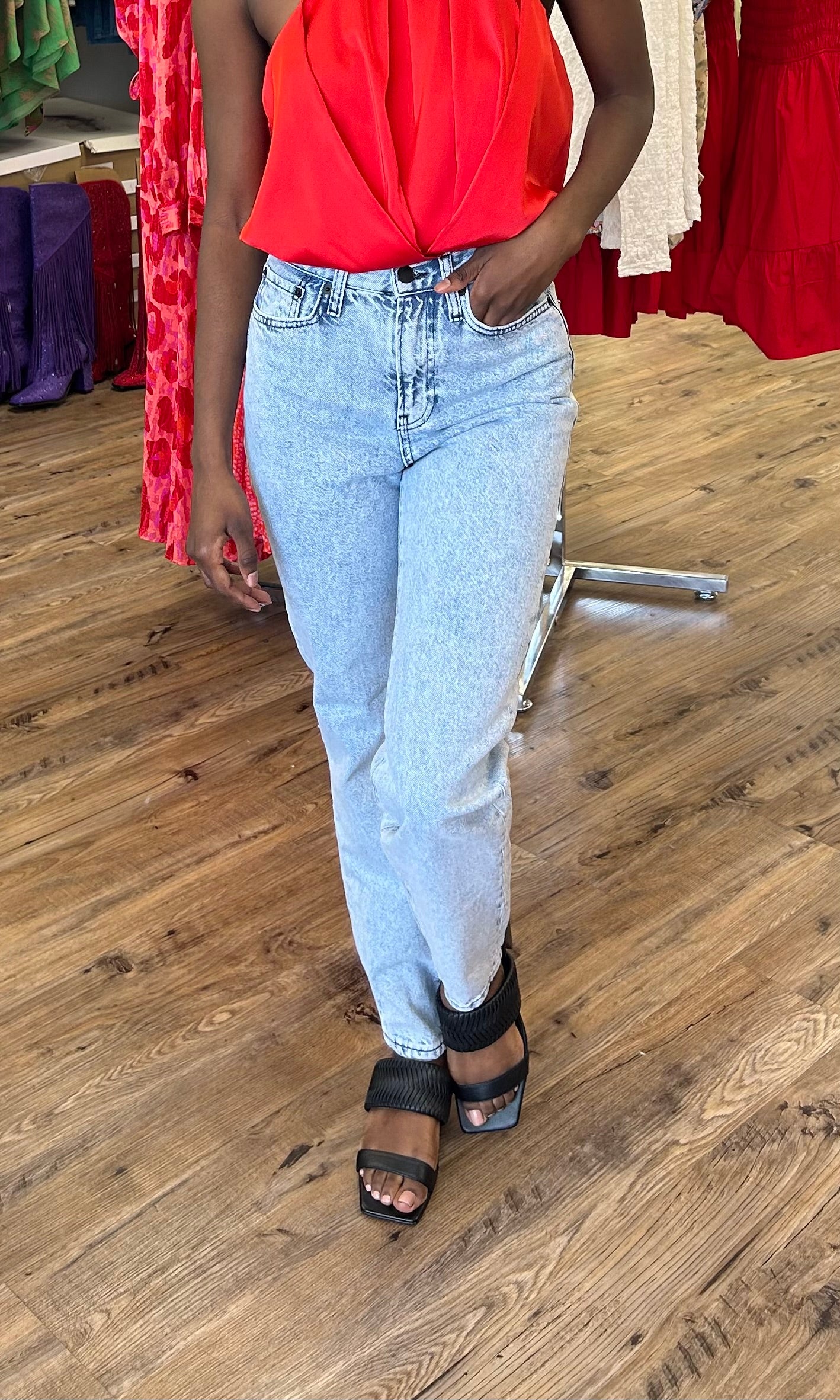 Model wearing Cherry Bomb Jeans in light blue denim with cherry on pocket, featuring a high-rise waist, wide leg fit, and raw hem detailing.