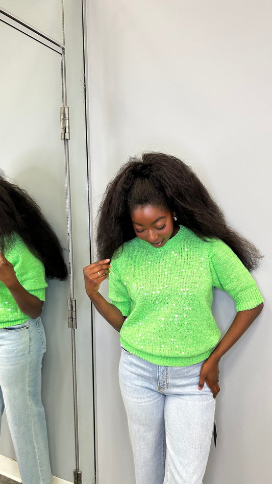 Model wearing the Chloris Top in vibrant green, featuring puff sleeves, ruched bodice, and a square neckline, styled with light denim jeans.