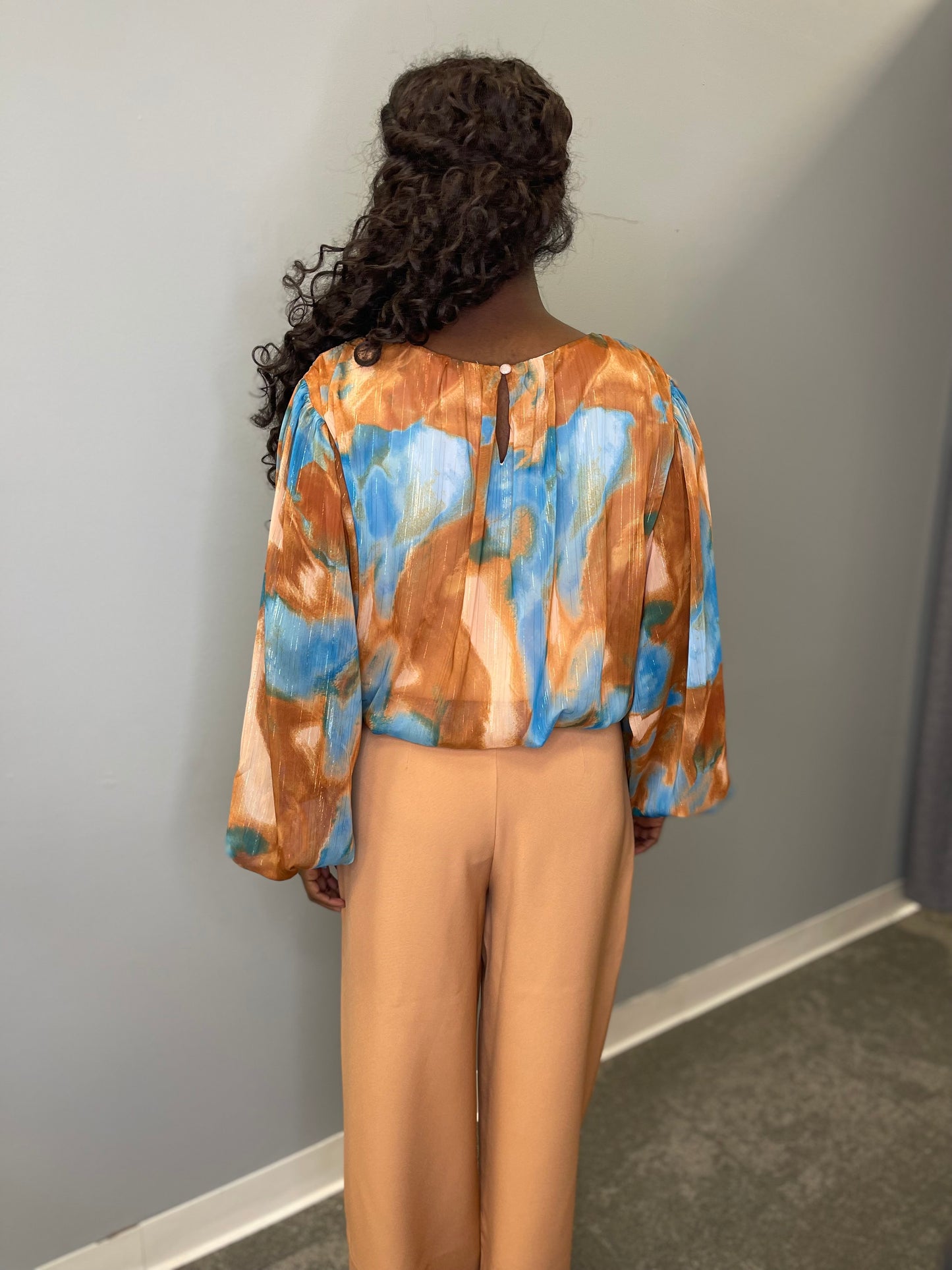Model wearing the Evermore Woven Top in brown and blue abstract pattern, featuring a relaxed fit and lightweight fabric.