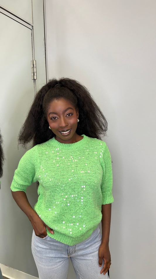 Model wearing the Chloris Top in vibrant green, featuring puff sleeves, ruched bodice, and a square neckline, styled with light denim jeans.