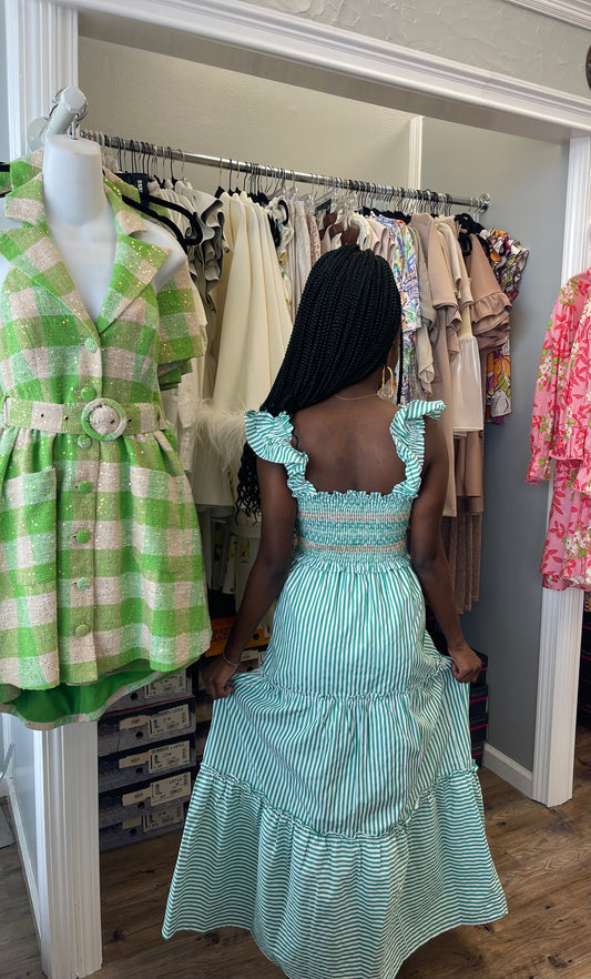 Model wearing the Peal Maxi Dress in green, featuring a tiered full-length skirt, fitted bodice, and delicate ruffle detailing.
