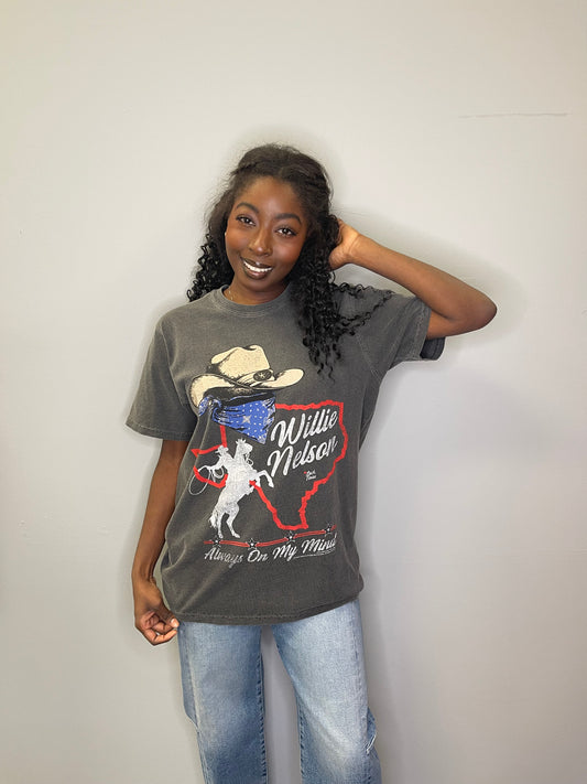 Model smiles with hand in hair, wearing the “Always On My Mind” tee front-facing, showcasing the vintage cowboy and Texas graphic.