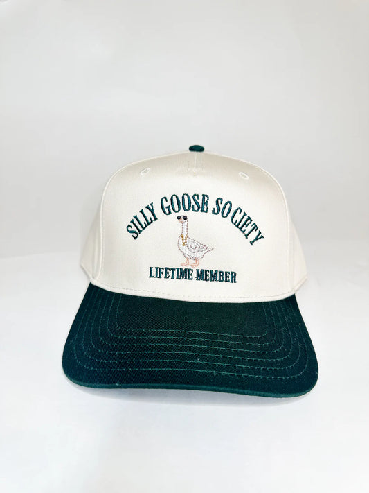 Cream and green trucker hat with "Silly Goose Society" and "Lifetime Member" embroidered on the front, featuring a cartoon goose wearing sunglasses.